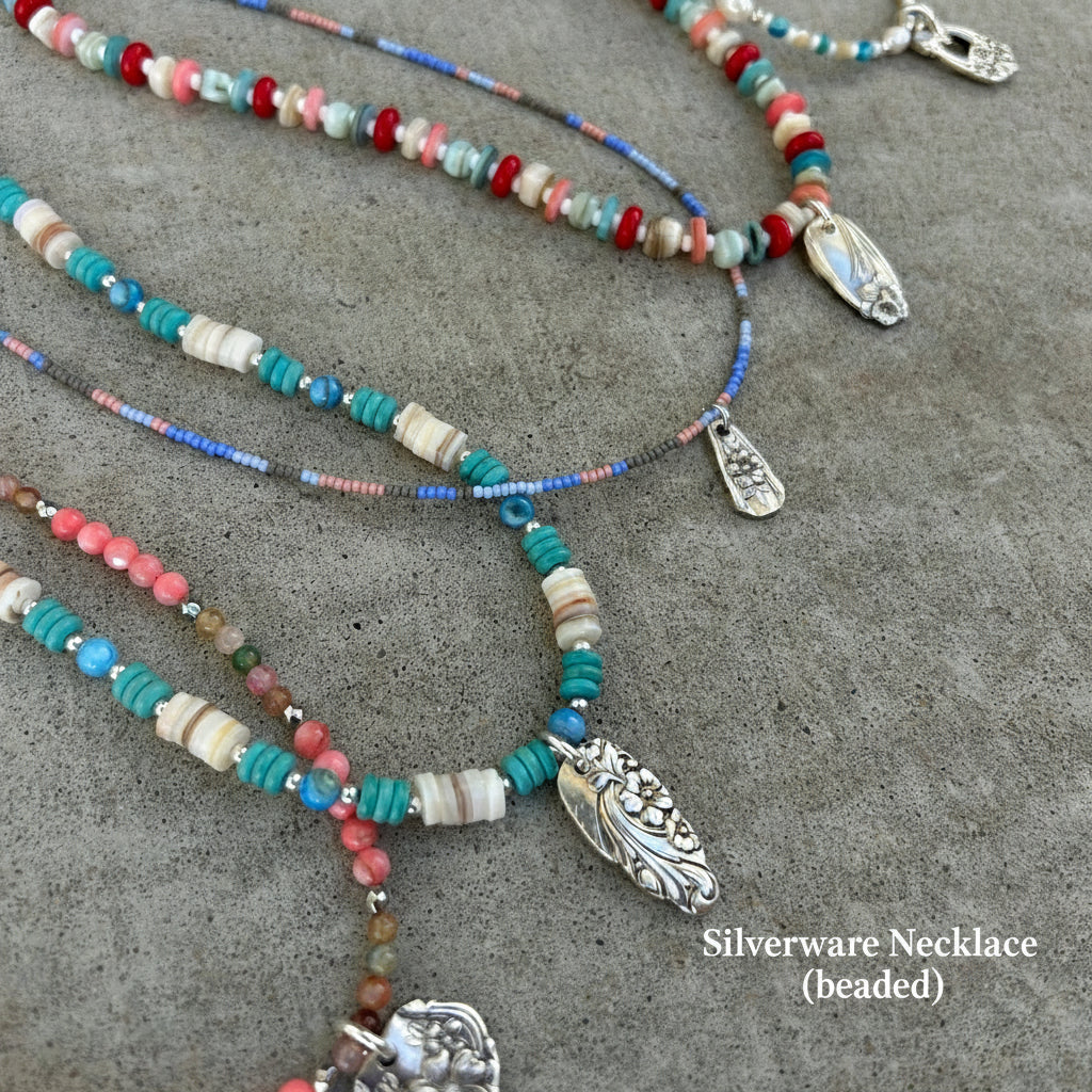 Colorful beaded necklaces with metal clasps on a gray surface and silverware pendants